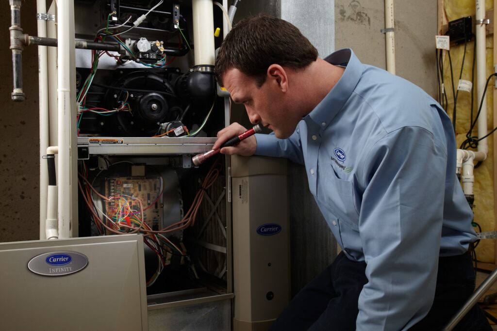 Furnace technician inspecting a home heating system with a flashlight